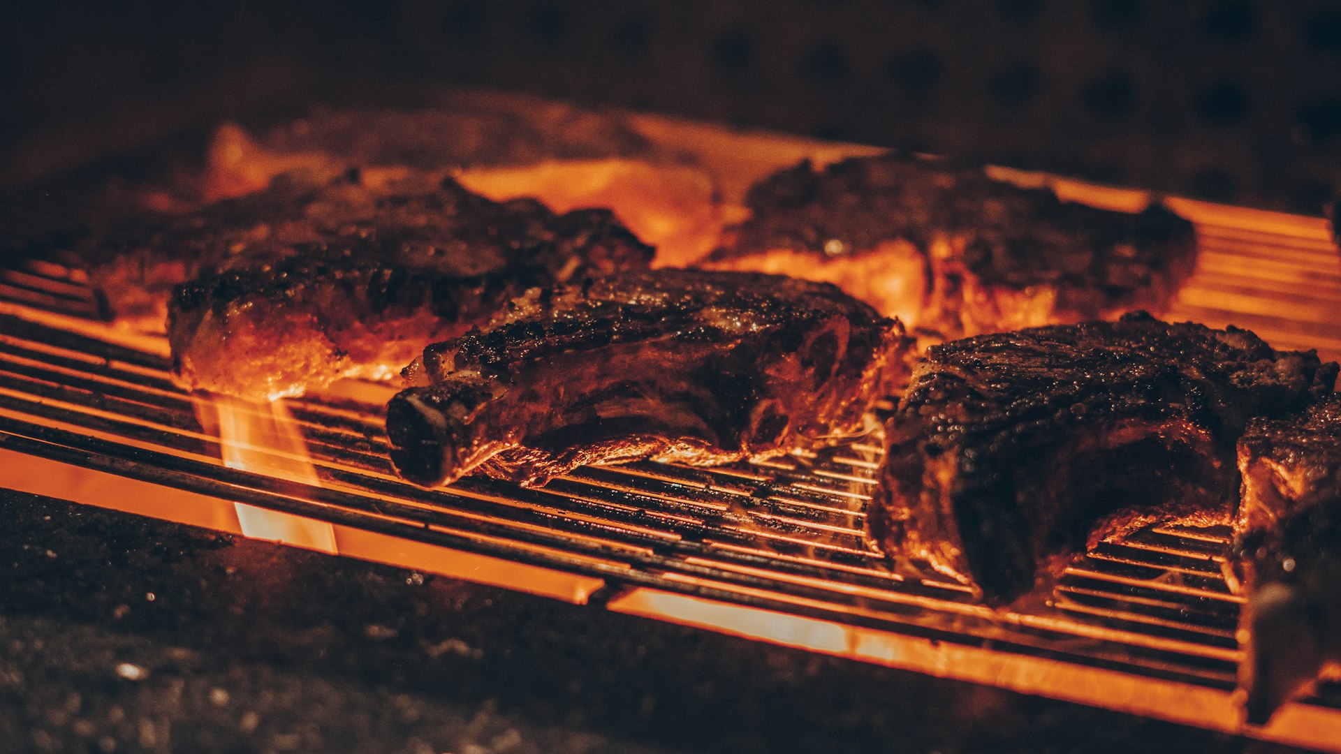person holding fork and knife slicing meat on black grill